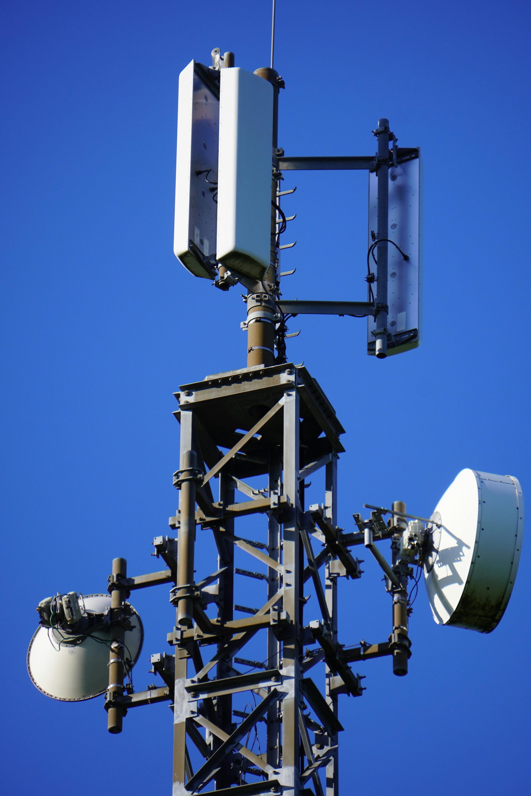 Close-up view of a communication tower highlighting antennas and technology against a clear blue sky.