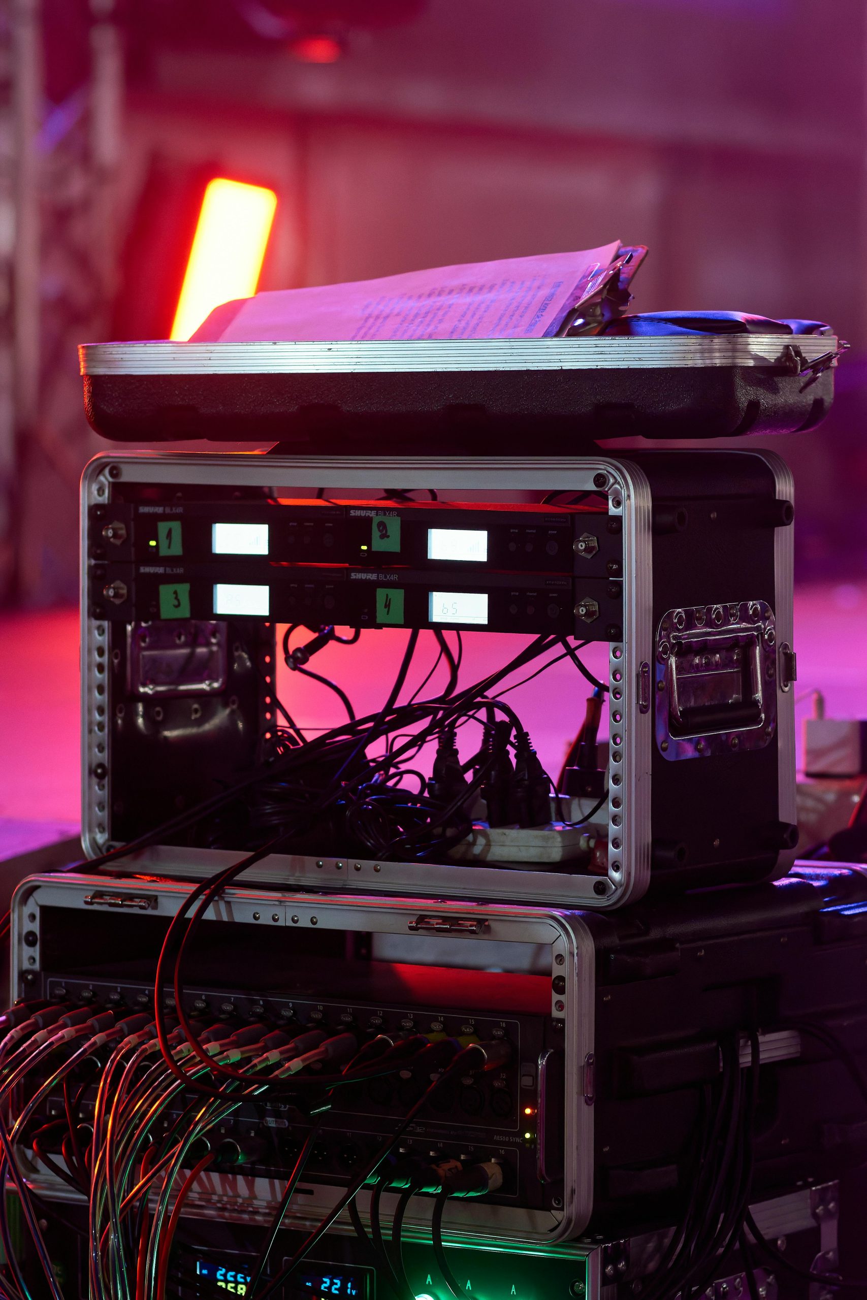 Close-up of audio equipment with colorful stage lights at a live event, showcasing professional sound gear.